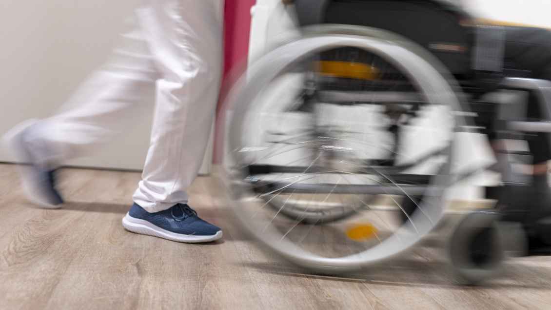 Pfleger schiebt einen Rollstuhl