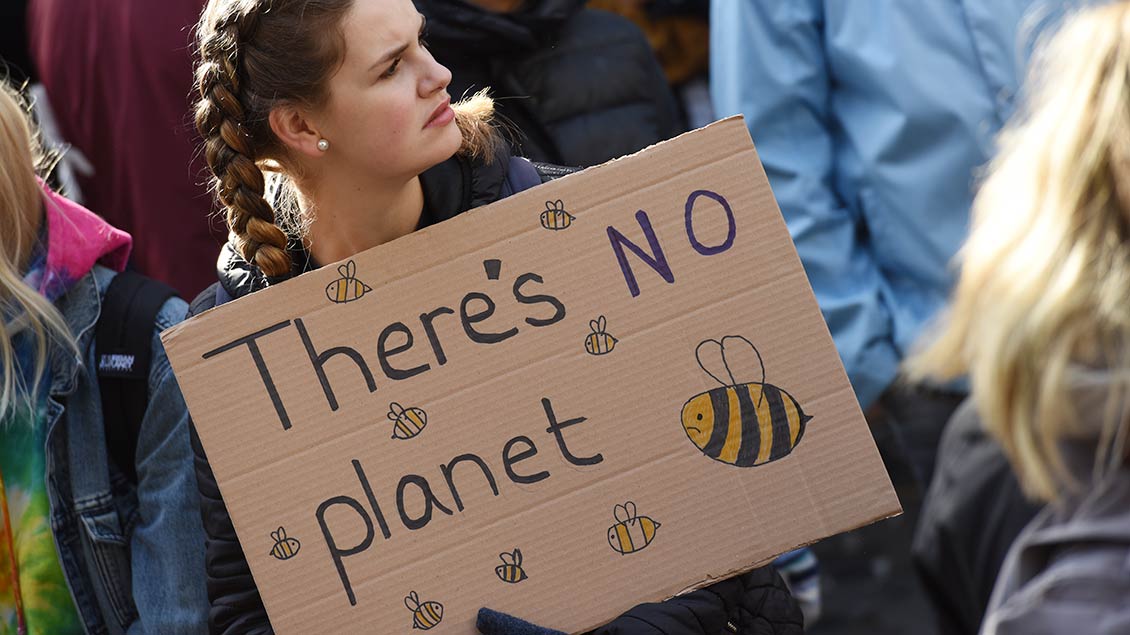 Eine junge Frau demonstriert mit einem Schild gegen den Klimawandel.