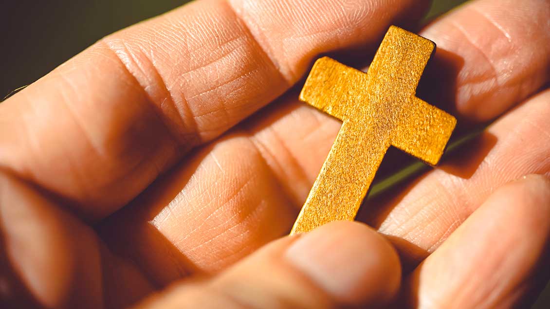 Ein kleines Holzkreuz liegt auf einer Handfläche Foto: Christian Ohde