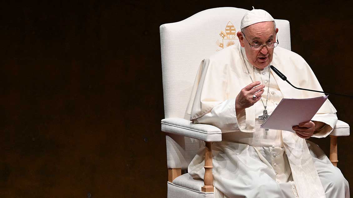 Papst Franziskus sitzt und hält eine Rede.
