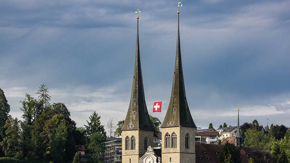 Türme der Kirche St. Leodegar in Luzern mit schweizer Nationalflagge