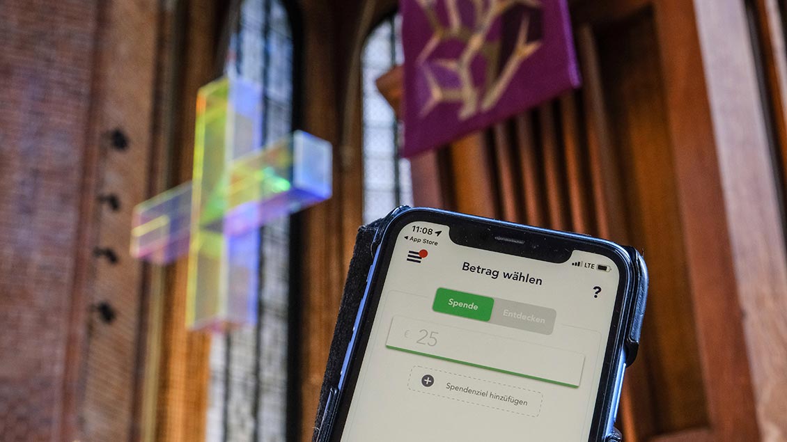 Smartphone mit der App Givt in einer Kirche