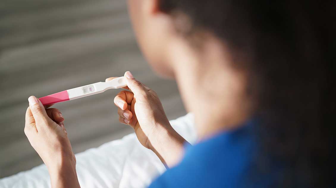 Frau blickt auf Schwangerschaftstest
