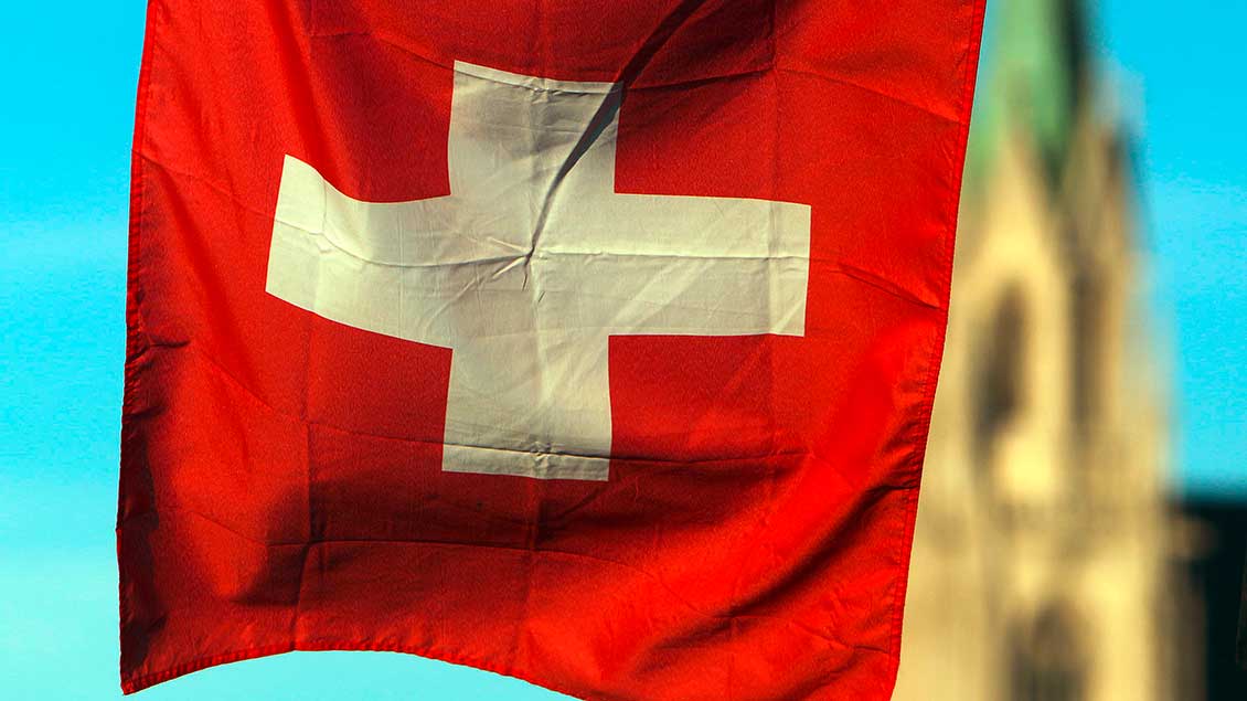 Schweizer Flagge vor einem Kirchturm
