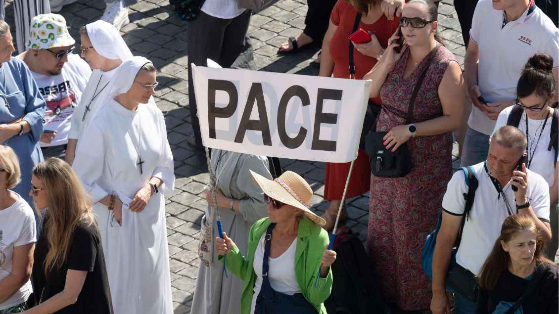 Eine Frau hält ein Schild für den Frieden auf dem Petersplatz hoch
