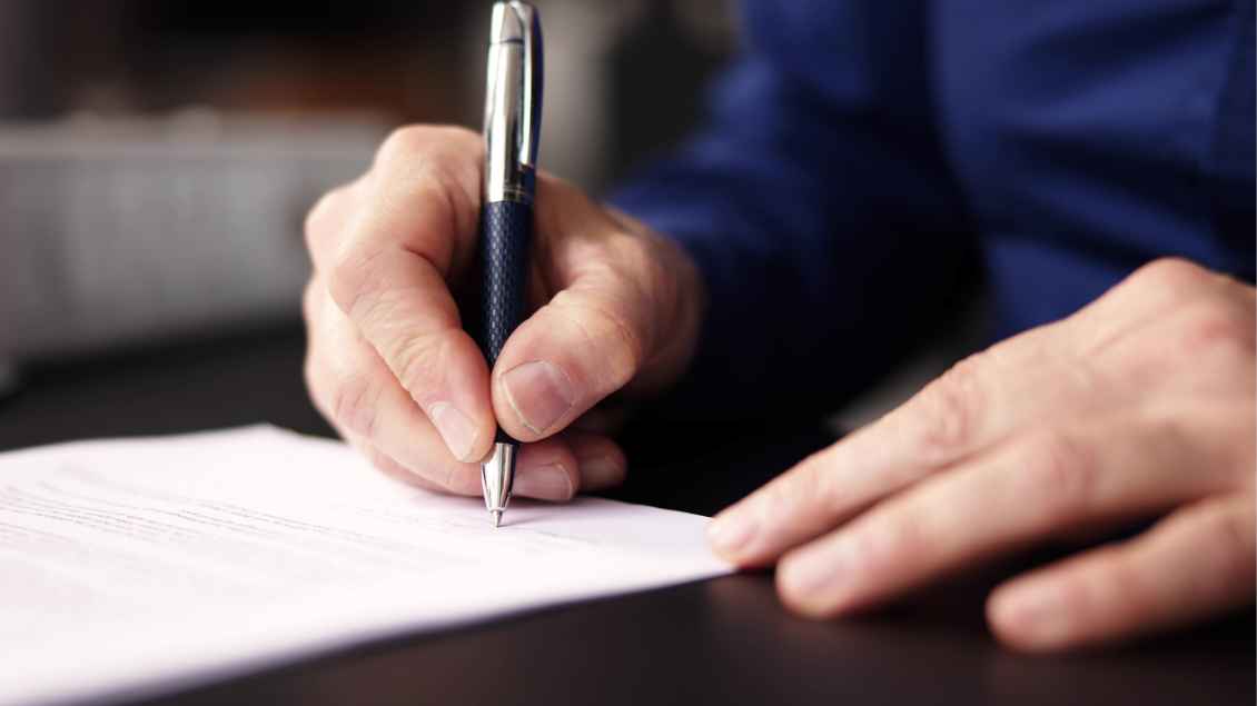Eine Person unterschreibt ein Dokument