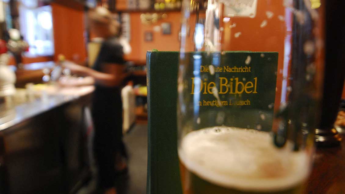 Bierglas vor einer Bibel auf einem Kneipentresen