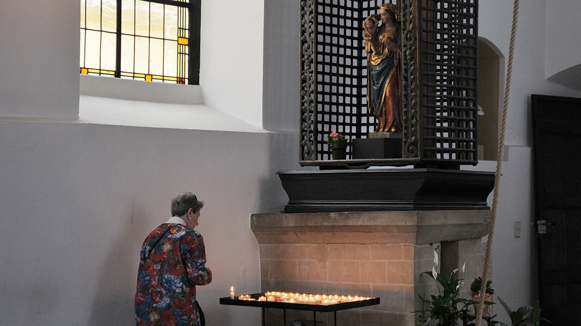 Eine Frau zündet in der Gastkirche eine Kerze an
