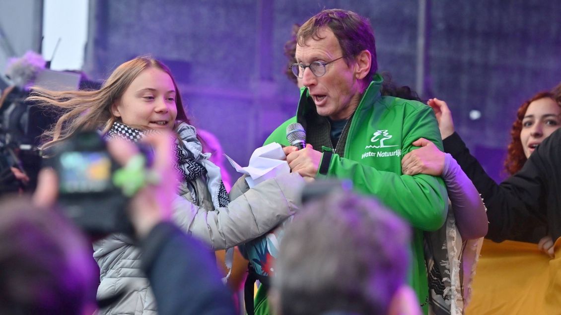 Ein Mann in grüner Jacke reißt Greta Thunberg das Mikrofon aus der Hand.