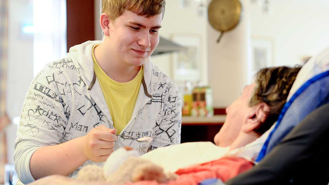 Ein junger Mann hilft einem Menschen mit Behinderung beim Essen
