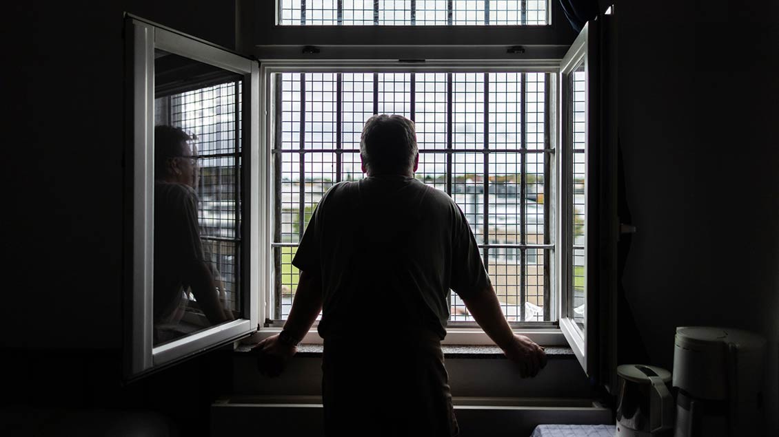 Ein Mann schaut aus einem Fenster einer Gefängniszelle