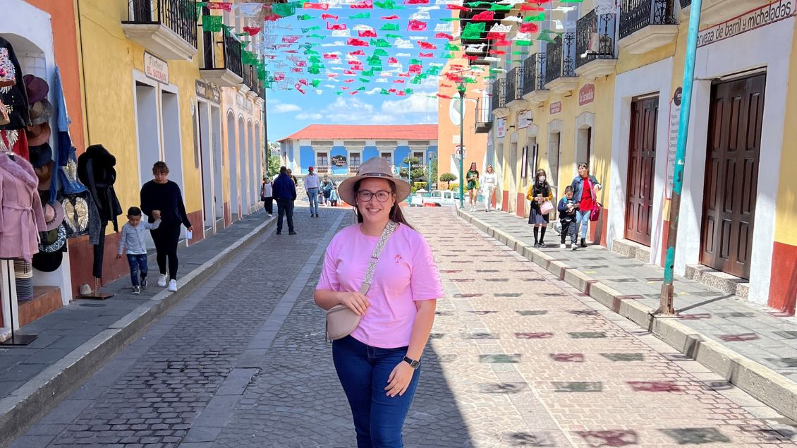 Xenia Doskal steht auf einer Straße in Mexiko. Über ihr hängen bunte Girlanden.