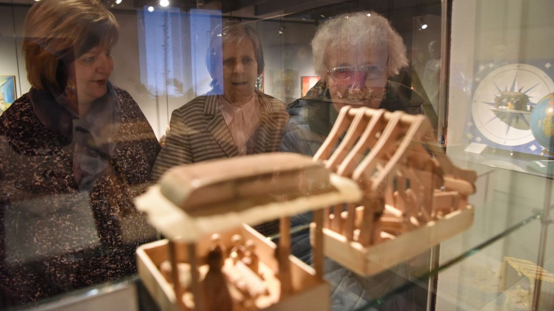 Ältere Frauen schauen in einen Austellungskasten mit Krippen.