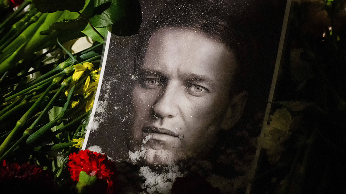 Eine rote Rose liegt auf einem Foto von Alexei Navalny.