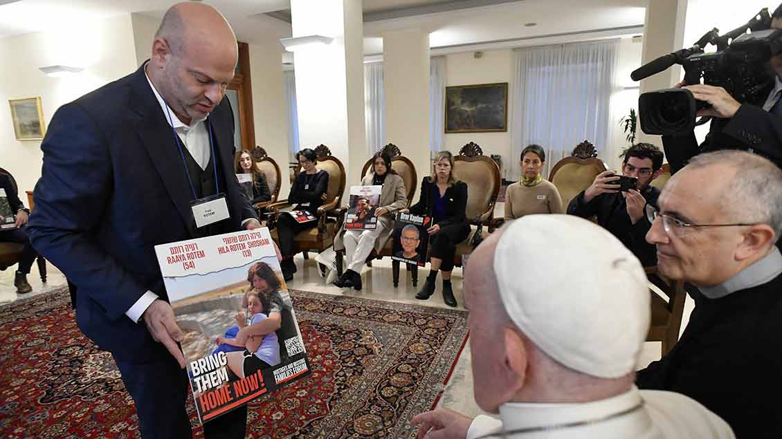 Ein Mann zeigt dem Papst ein Plakat